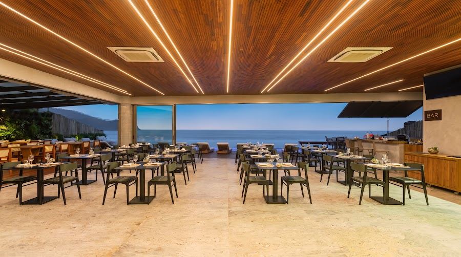 O restaurante do Duke Beach com as portas abertas para o mar, mesas postas no fim da tarde.
